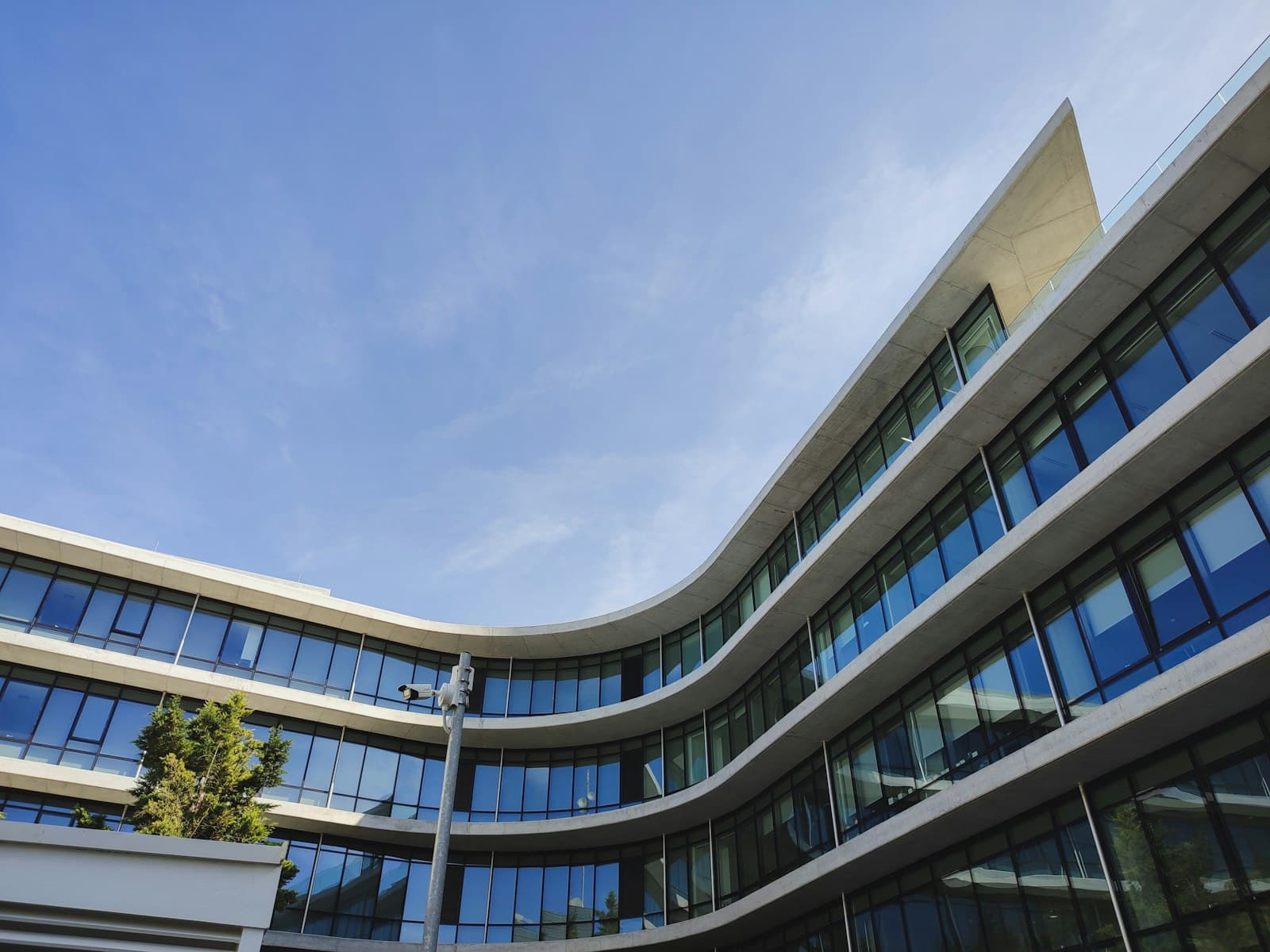 Modern glass office building photographed from below against a clear sky